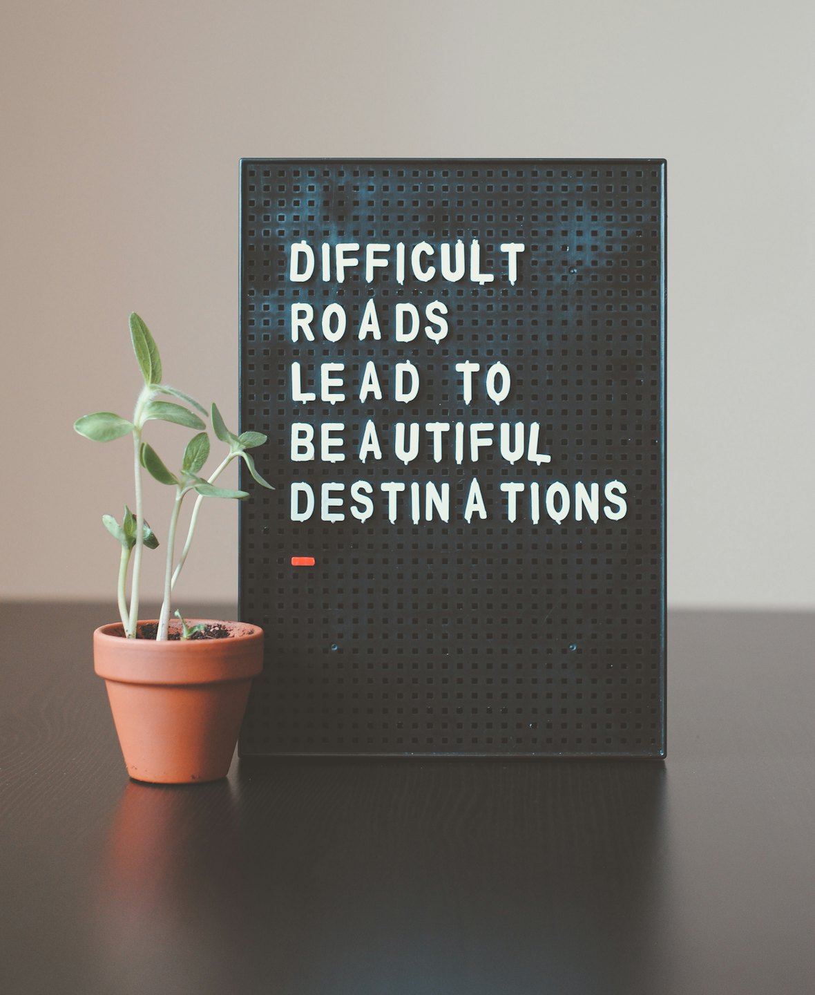 Een bord met de tekst: 'Difficult roads lead to beautiful destinations'